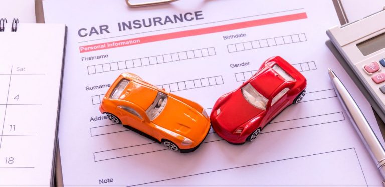 Two toy cars, red and orange, placed on top of a car insurance form.